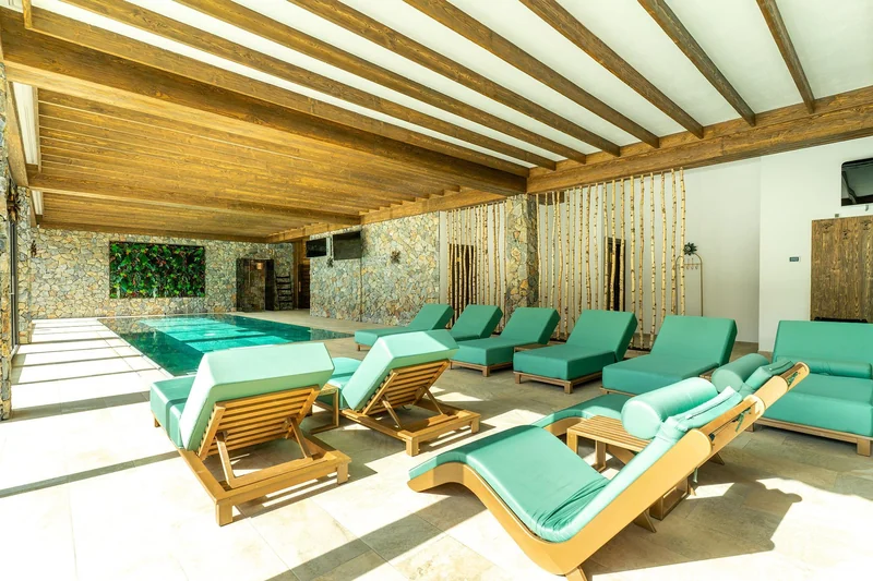 Piscina interioară cu șezlonguri și pereți de sticlă